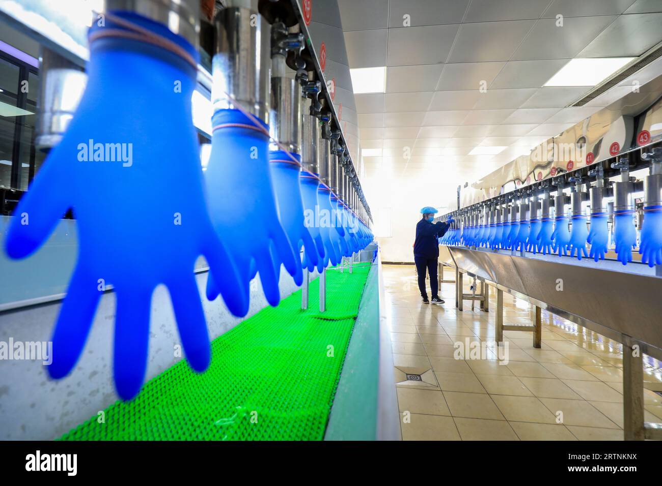 LUANNAN COUNTY, China - 27. Dezember 2021: Arbeiter testeten die Qualität von Nitrilhandschuhen durch Wasserinjektionstest in einer medizinischen Versorgungsmaterialproduktion Stockfoto