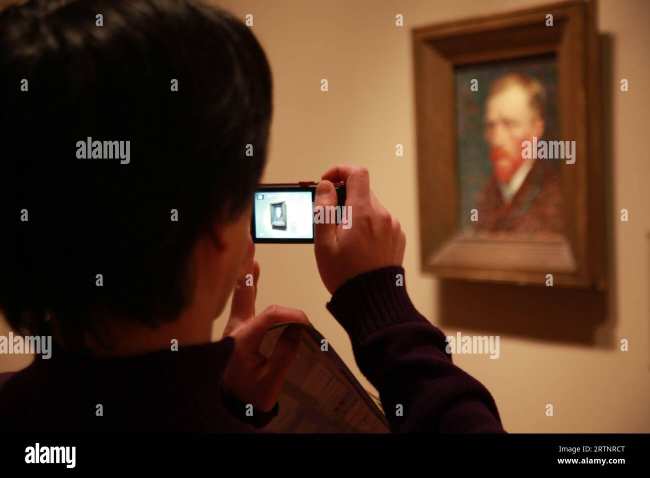 Der Besucher fotografiert ein Selbstporträt von Vincent van Gogh mit seinem Handy in einem Museum in Chicago, Ill Stockfoto