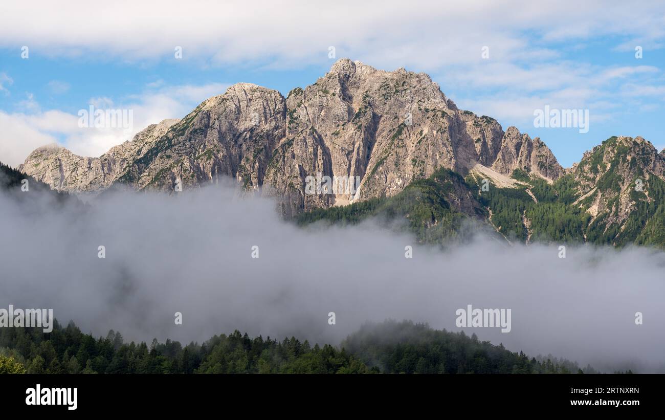 Ein Berggipfel, der sich über den Wolken der Julien Alpen in Slowenien erstreckt Stockfoto