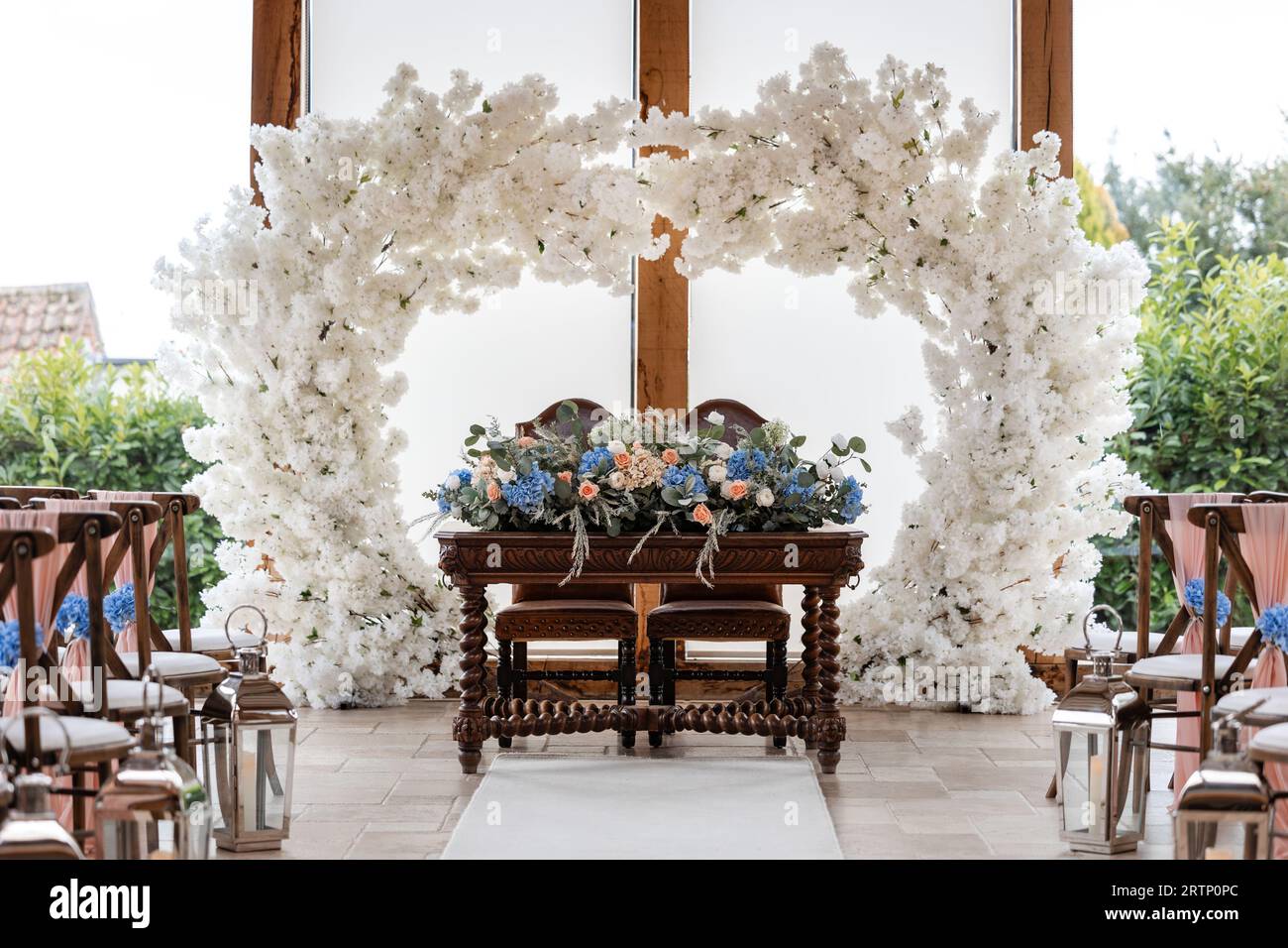 Wunderschöne Sitzplätze für Hochzeitsfeiern mit Blumenbogen und Holzsitzen. Dekoration und romantischer Hintergrund. Stockfoto