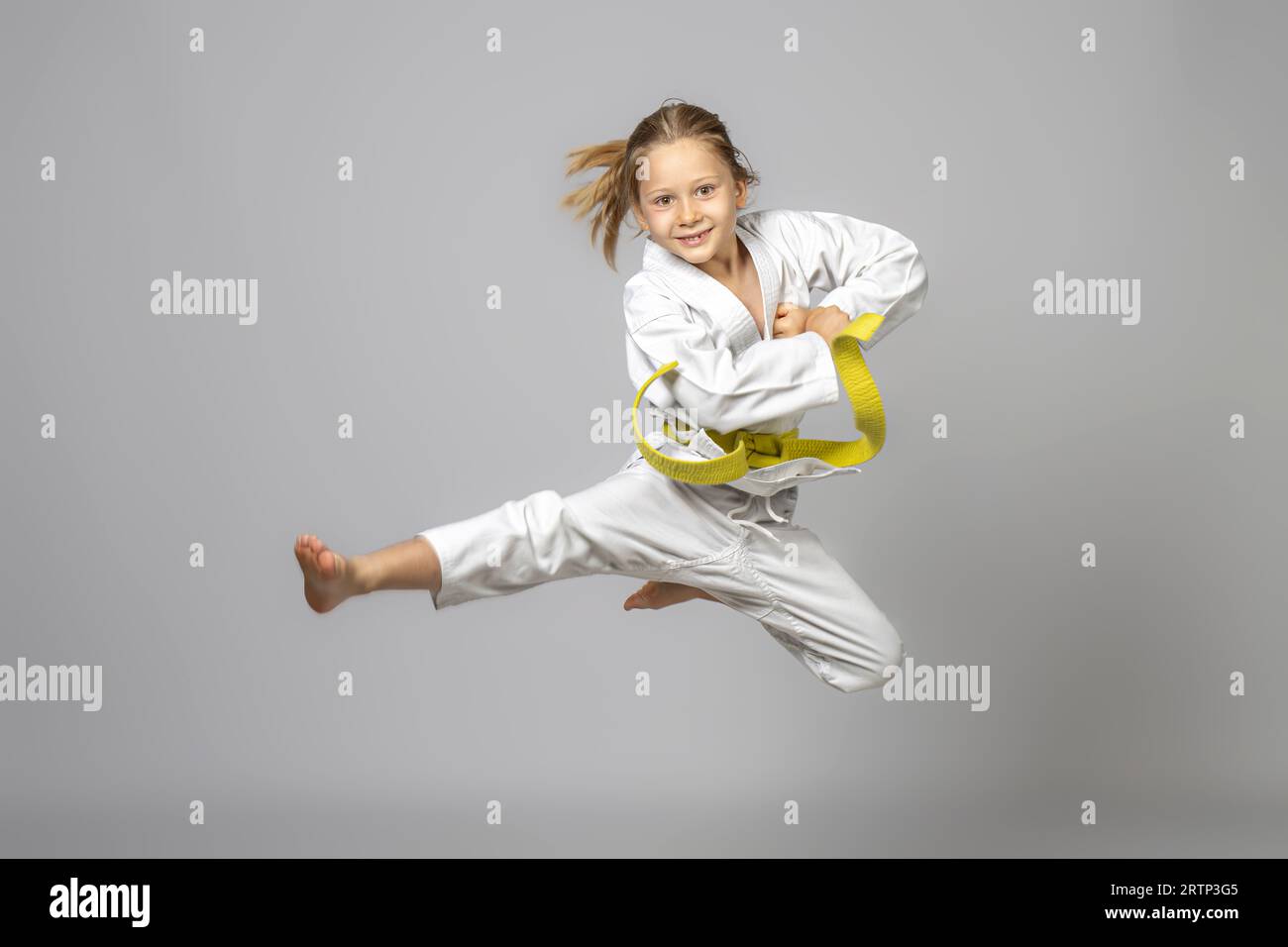 Glückliches Kind, das Kampfkunst übt, führt einen Sprung durch, Studio-Shoot Stockfoto