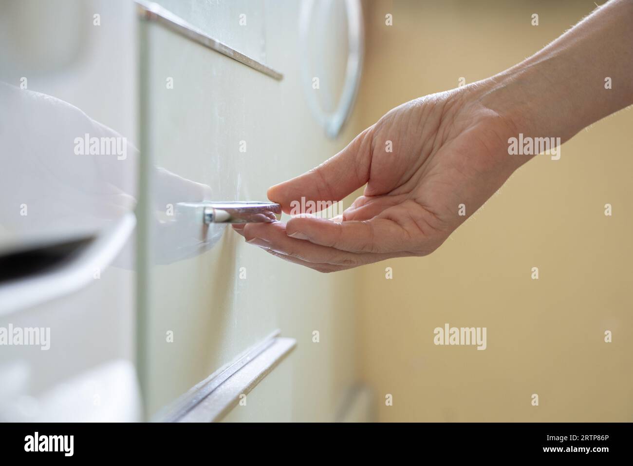 Die Hand der Frau öffnet den Küchenschrank unter Sonnenlicht, Küchenmöbel zu Hause Stockfoto