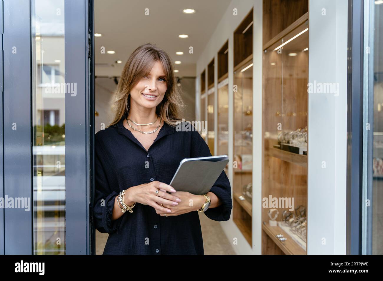 Manager der Luxus-Schmuck-Boutique mit digitalem Tablet vor der Tür. Offene Wartezeiten für Kunden. Konzept für kleine Unternehmen. Stockfoto