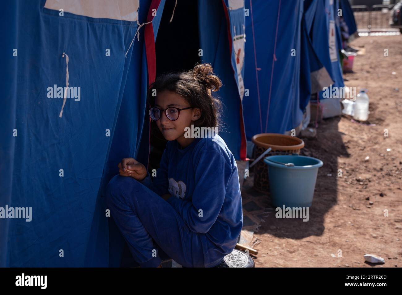 Marokko. September 2023. Ein Mädchen sitzt vor einem Zelt und dient als provisorisches Zuhause für Menschen, die ihre Häuser durch das Erdbeben verloren haben. Die Dorfbewohner in Imlil in den Toubkal-Bergen kommen noch immer mit der Zerstörung zurecht, die das Erdbeben am vergangenen Freitag angerichtet hat. Da viele Häuser beschädigt oder zerstört wurden, wurden Dorfbewohner in Zelte verlegt und werden von Ärzten aus einem nahe gelegenen Militärkrankenhaus in Asni betreut, wo täglich etwa 600 Menschen behandelt werden. Fast 3.000 Menschen sollen bei dem Erdbeben ums Leben gekommen sein. (Bild: © Ashley Chan/SOPA Images via ZUMA Pres Stockfoto