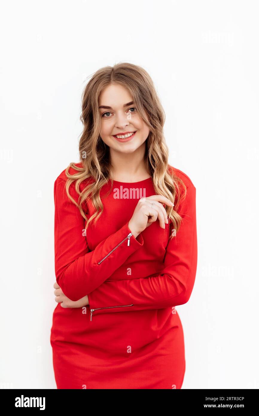 Frau in rotem Kleid mit lockigem Haar auf weißem Hintergrund. Studioportrait eines Mädchens. Stockfoto