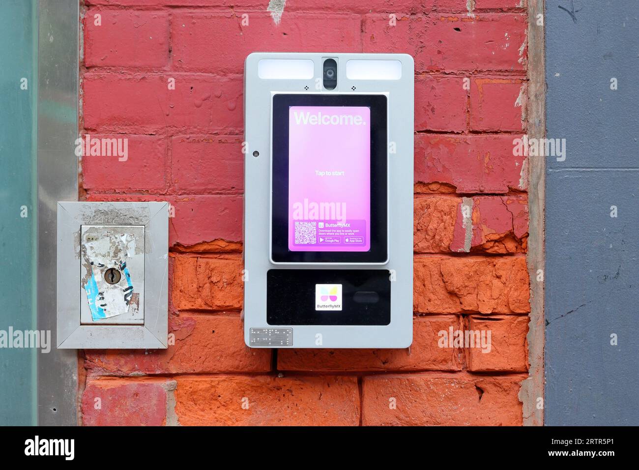 Eine USPS-Schlüsselaufbewahrungsbox neben einem ButterflyMX-Smart-Intercom-System zur Türzugangskontrolle in einem NYC-Wohngebäude. Stockfoto