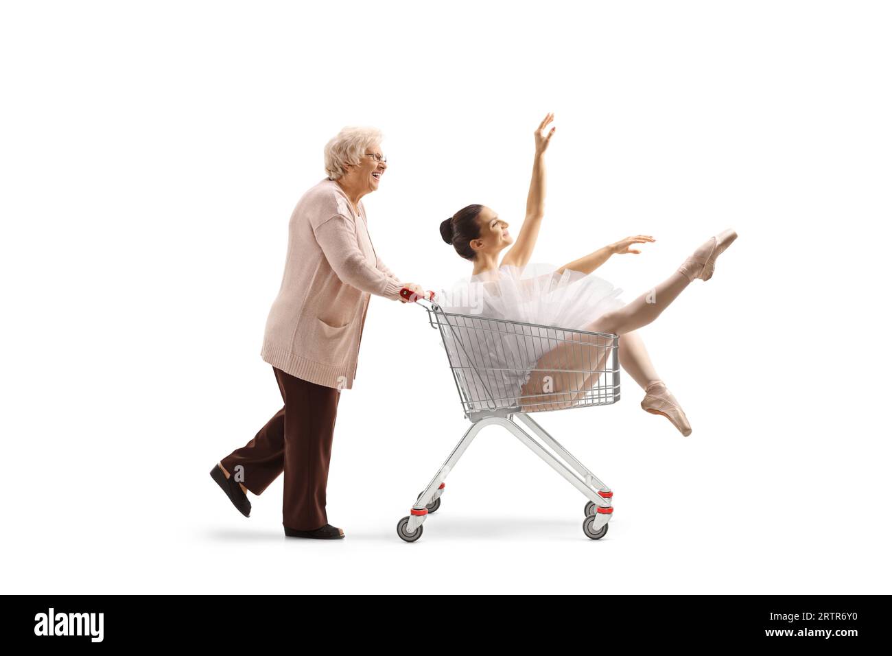 Ältere Frau, die eine Ballerina in einen Einkaufswagen schiebt, isoliert auf weißem Hintergrund Stockfoto