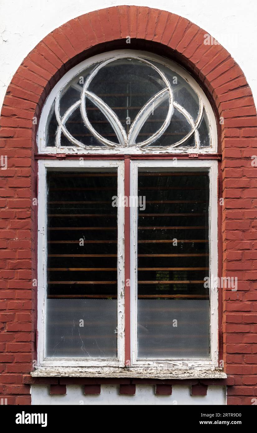 Fenster mit Bogen in weißem Holzrahmen in einer Steinmauer mit Backsteinrahmen. Svetlogorsk, Kaliningrad Oblast, Russland Stockfoto