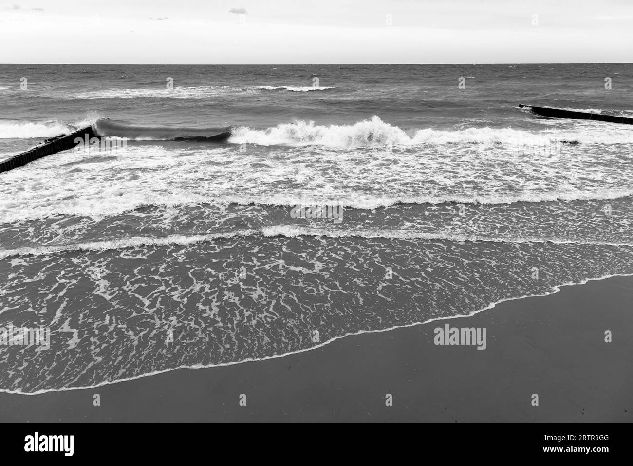 Blick auf den Strand mit Uferwasser und Wellenbrechern, Schwarzweißfoto. Landschaftsbild der Ostseeküste. Zelenogradsk, Oblast Kaliningrad, Russland Stockfoto