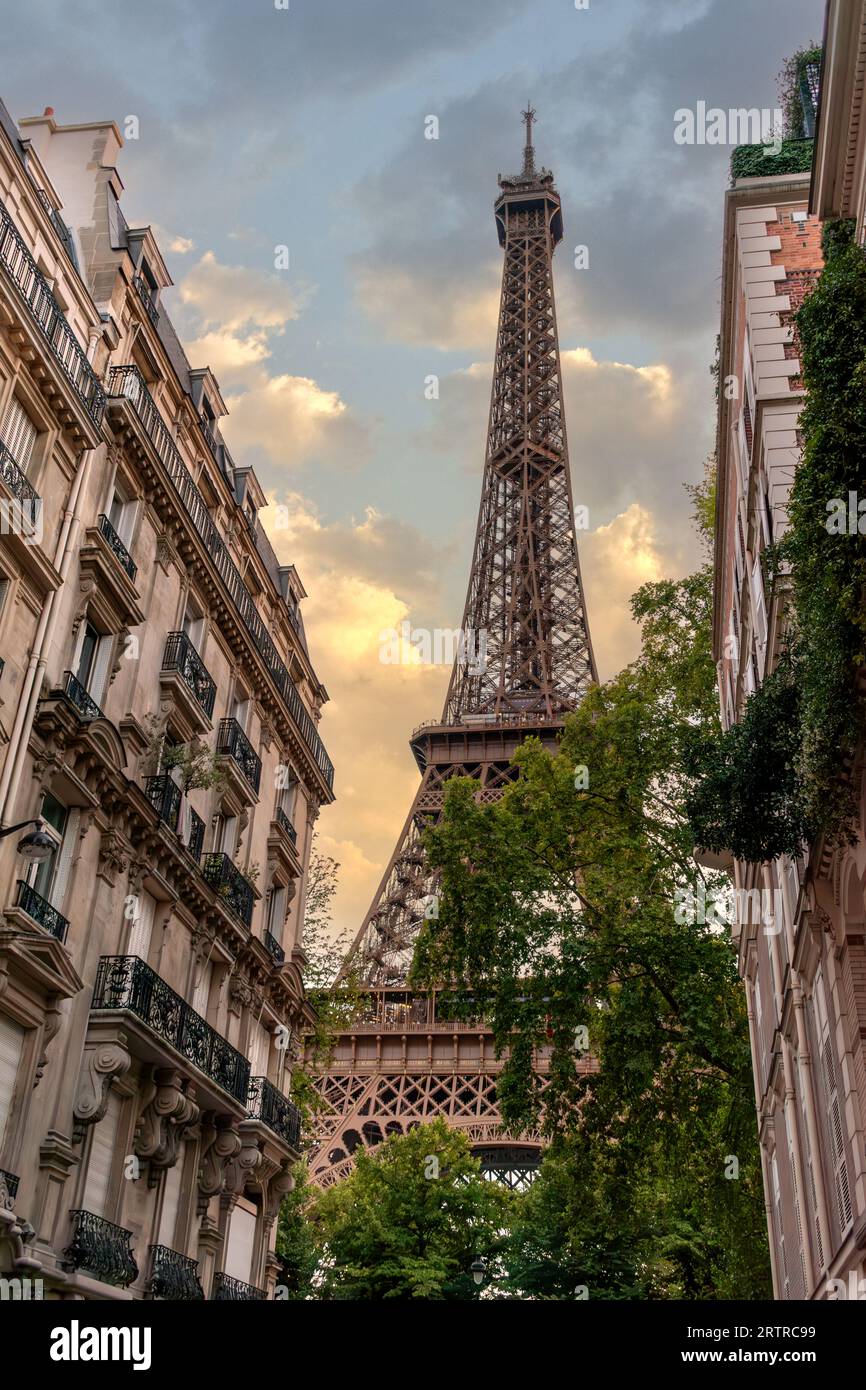 Tour Eiffel am Himmel mit farbigen Sonnenuntergangswolken zwischen historischen Gebäuden auf der Rue de l'Université in Paris. Vertikale Ansicht Stockfoto