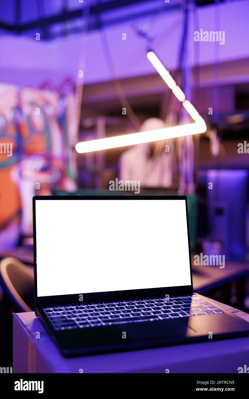 Laptop mit weißem, leerem Bildschirm für Ransomware in verlassenen Lagerhäusern. Tragbarer Computer mit leerem Display für schädlichen Softwarecode in der Nacht, in der sich Hacker verstecken Stockfoto