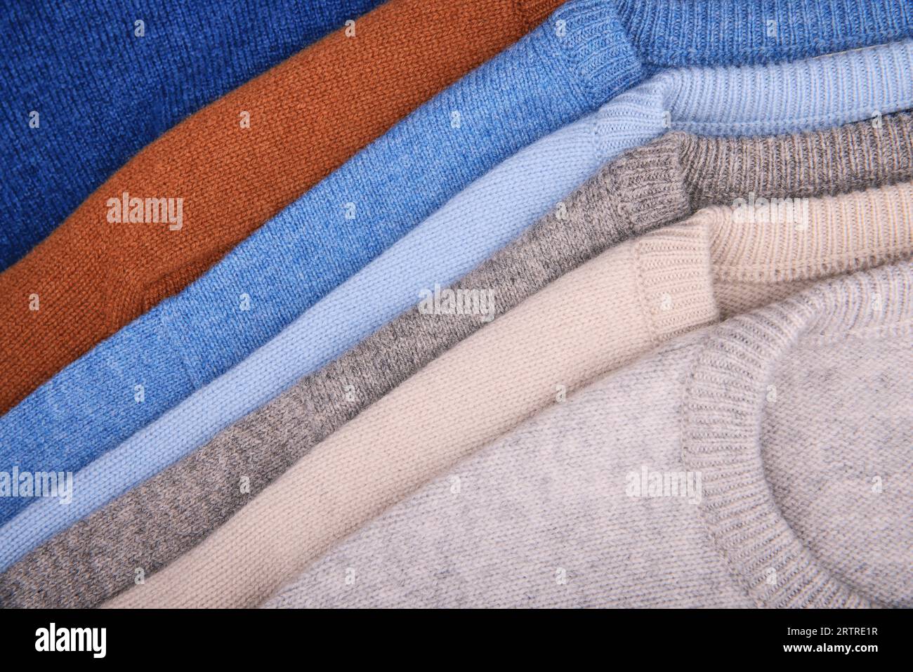Warme Pullover. Herbst, Winterkleidung. Metallgestell mit verschiedenen Pullovern auf Kleiderbügeln in einer modernen Modeboutique Stockfoto