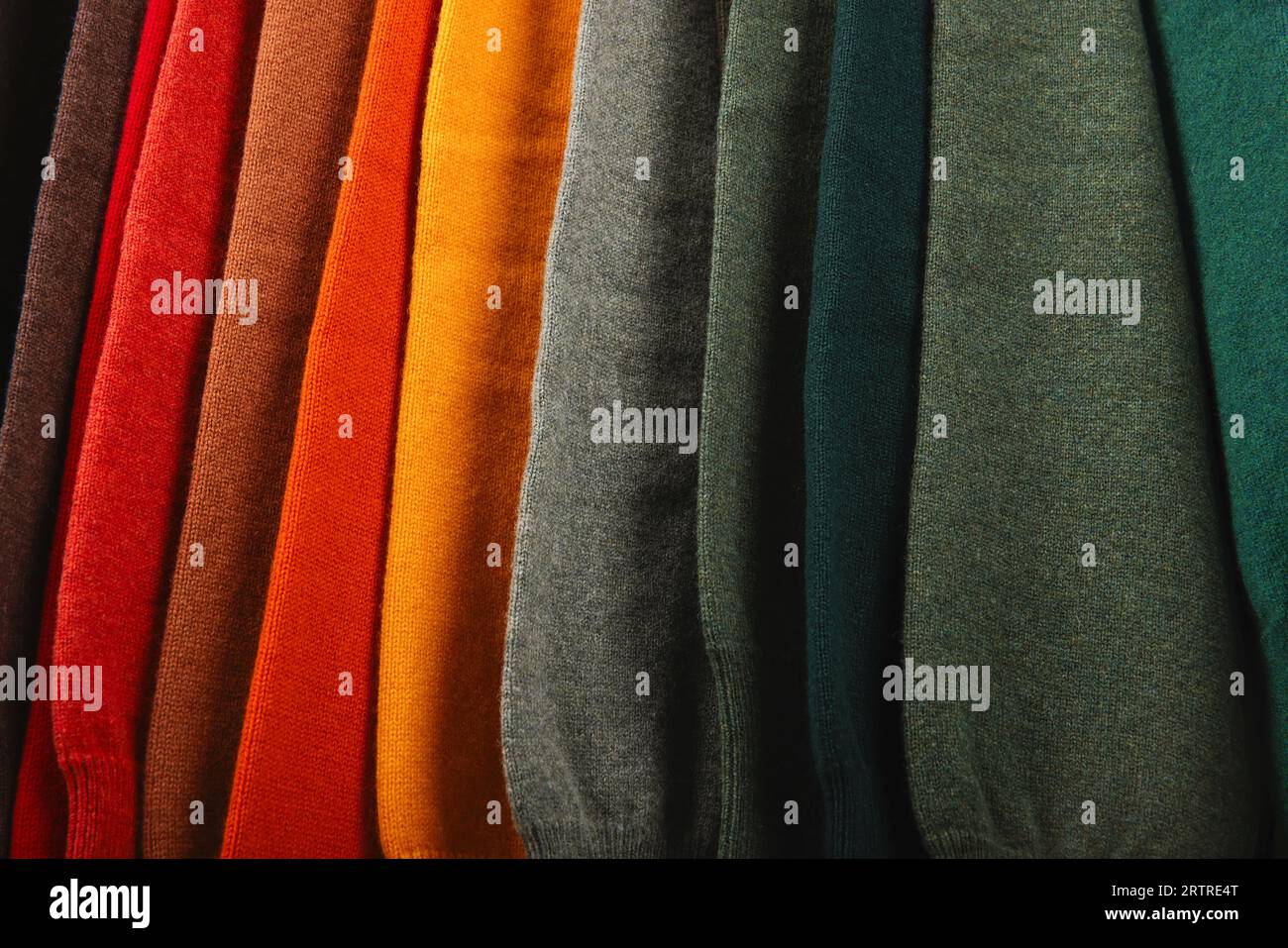 Warme Pullover. Herbst, Winterkleidung. Metallgestell mit verschiedenen Pullovern auf Kleiderbügeln in einer modernen Modeboutique. Leichtindustrie Stockfoto