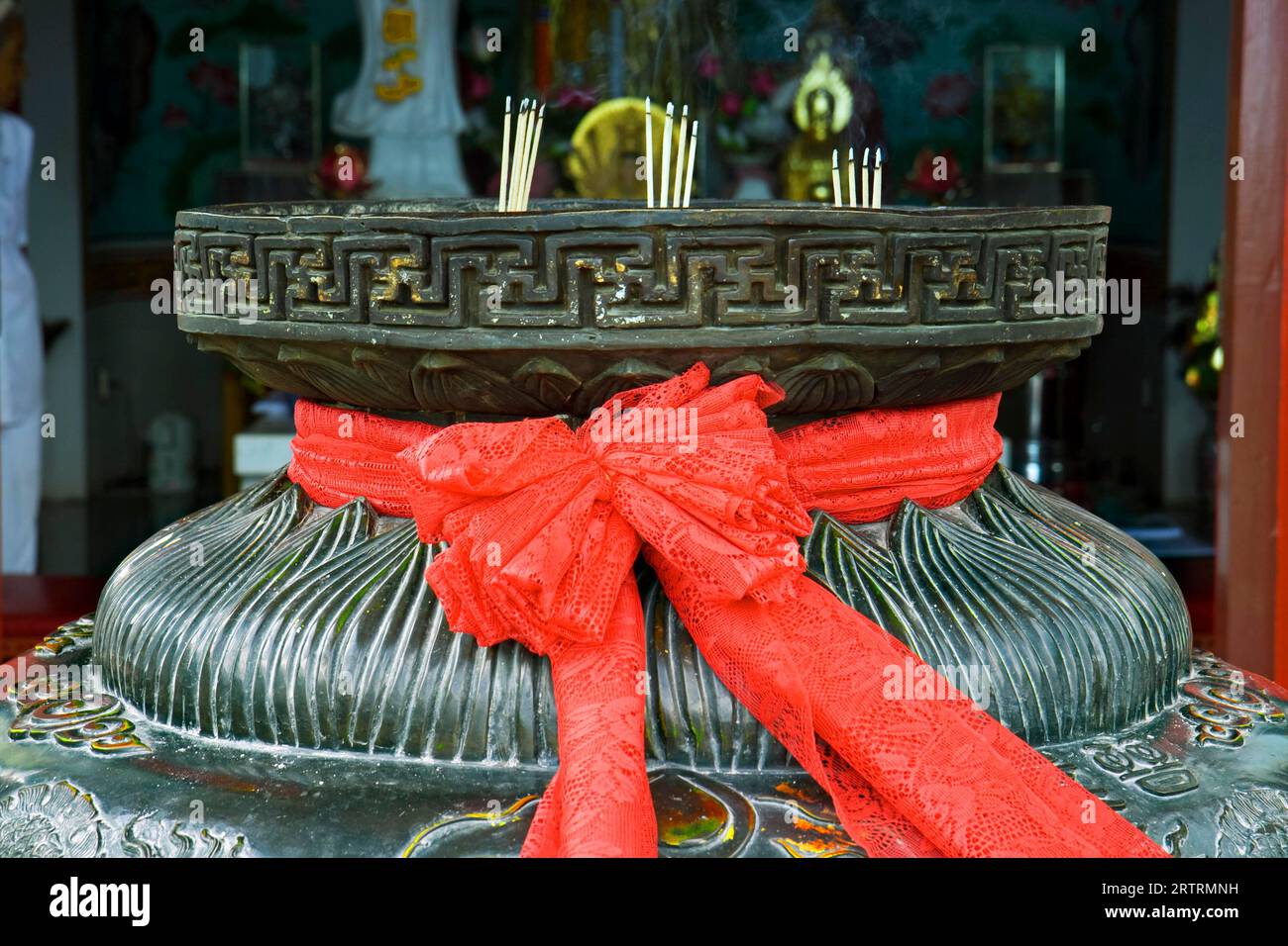 Rotes Band auf einer Schüssel für Räucherstäbchen vor einer Pagode, Thailand Stockfoto