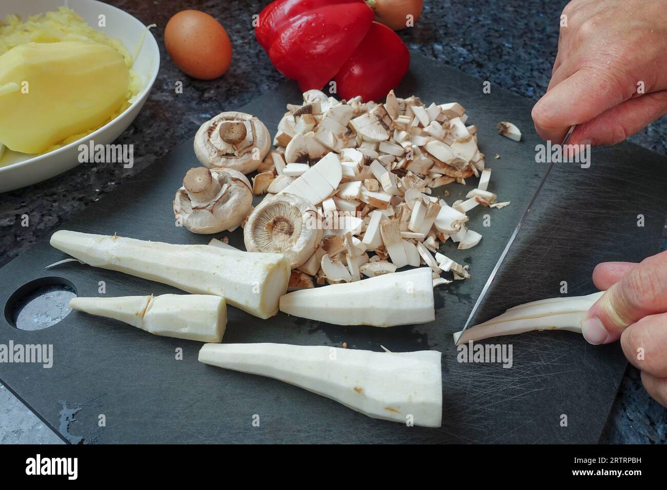 Schwäbische Küche, Zubereitung von deftigem Kartoffelstrudel, Petersilienwurzel, Schnittgemüse zum Füllen, Pilze, Kartoffeln auf der Rückseite gekocht und geschält Stockfoto