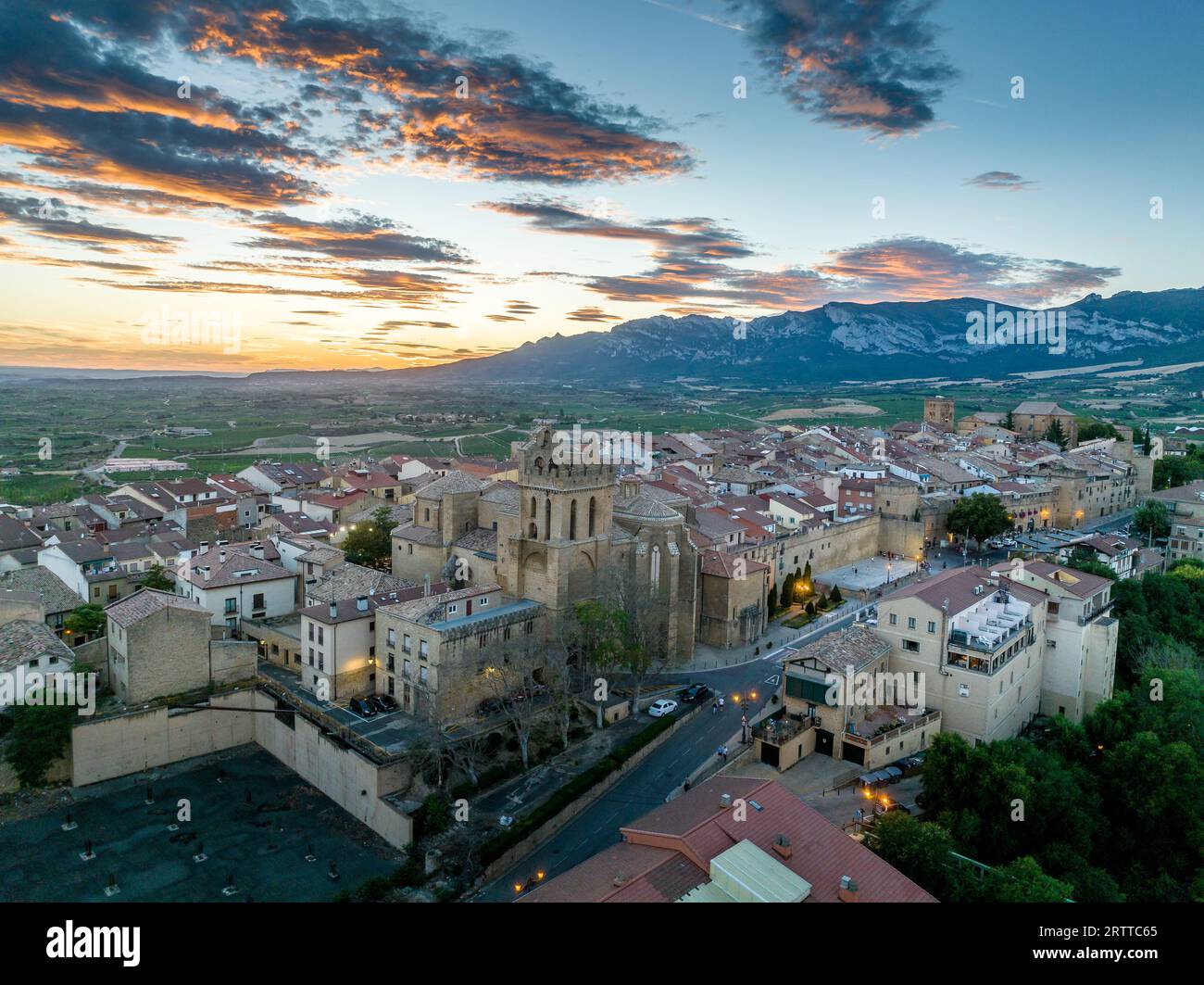 Blick aus der Vogelperspektive auf Laguardia mittelalterliches befestigtes Dorf auf einem Hügel, umgeben von Weingütern in der spanischen Region Rioja, mit farbenfrohem Sonnenuntergang Stockfoto