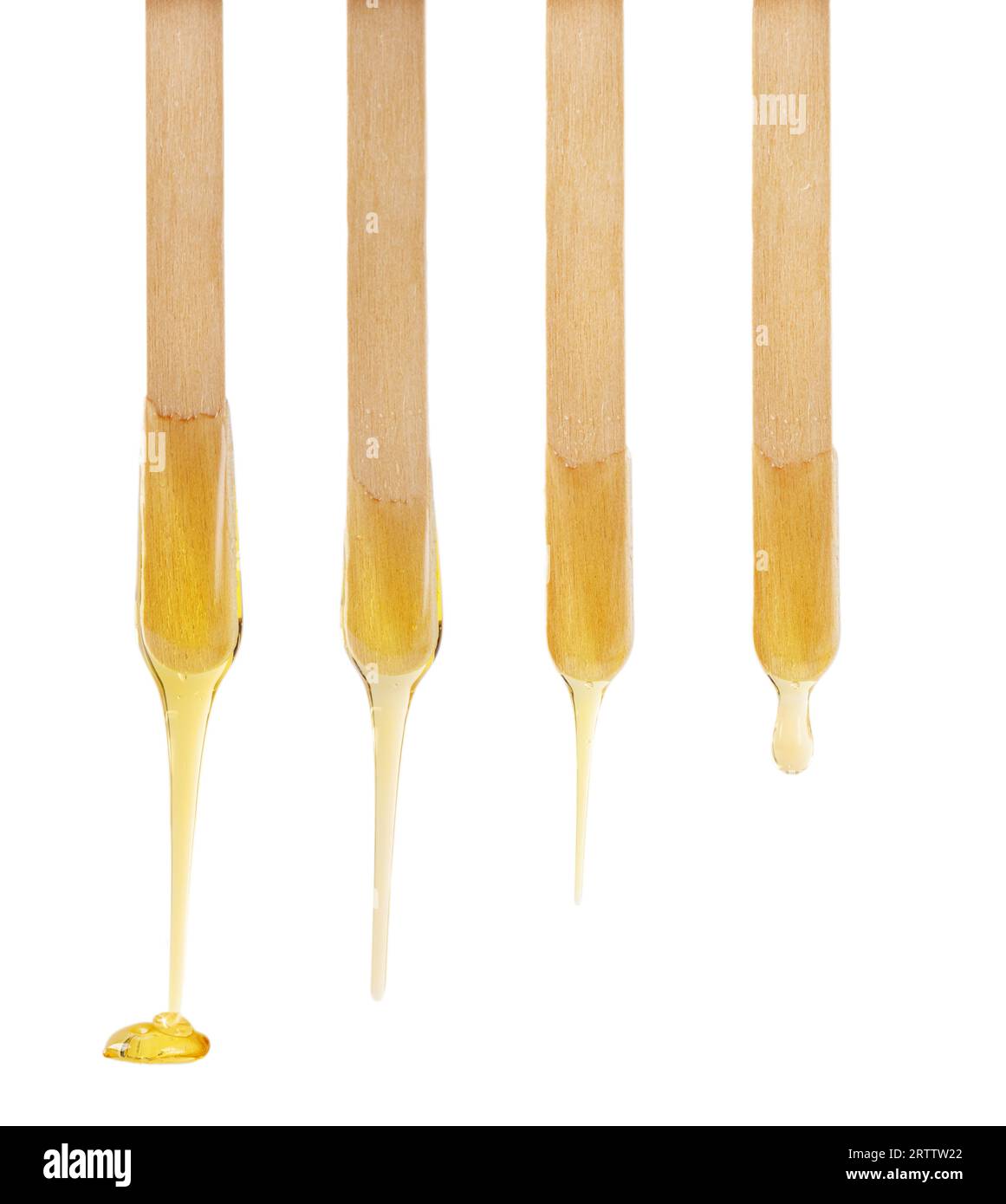Goldene Zuckerpaste oder Wachs für die Enthaarung, die vom Holzstab auf weißem Hintergrund tropft. Stockfoto