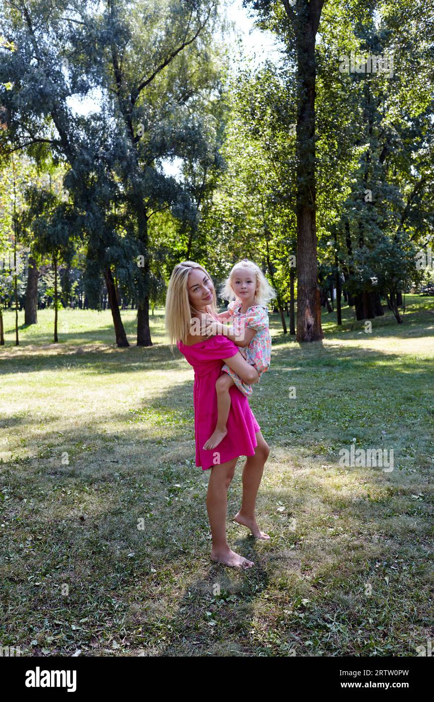 Mutter und Tochter gehen im Sommerpark spazieren. Kindheit, Freizeit und Menschen Konzept - glückliche Familie, Ruhe in der Natur und haben eine gute Zeit Stockfoto