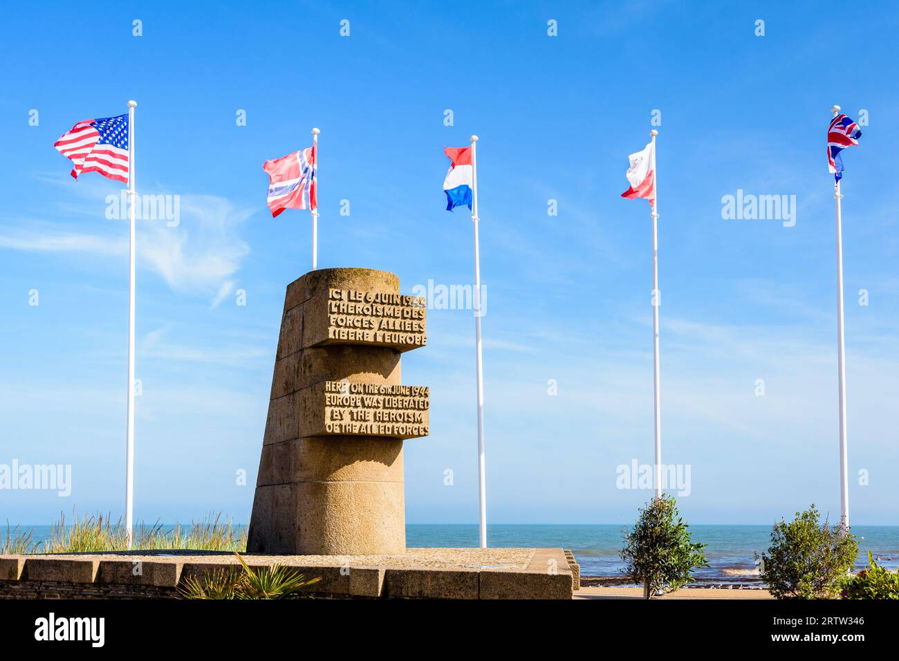 Signaldenkmal in Bernières-sur-Mer, Frankreich, errichtet im Jahr 1950 auf der Anlegestelle der Normandie im Zweiten Weltkrieg am Juno Beach, umgeben von den Flaggen der Alliierten. Stockfoto