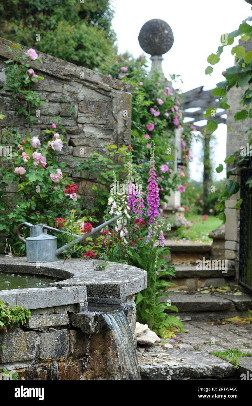 Gießkanne durch eine Wasserstelle in einem ummauerten Garten, Großbritannien Stockfoto