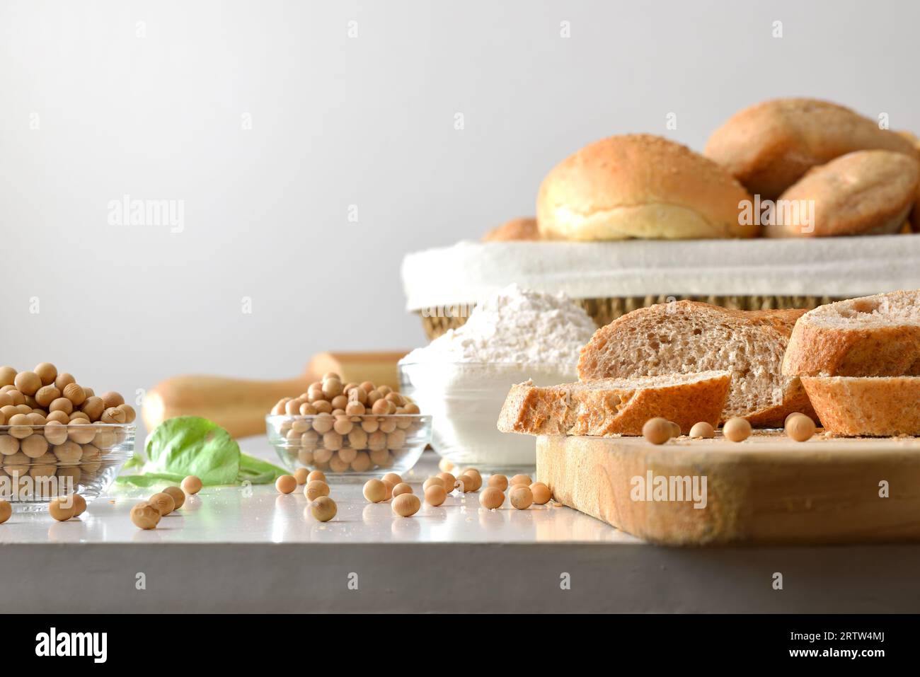 Brot mit Sojamehl auf Küchenbank mit Sojabohnen und weißem isoliertem Hintergrund. Vorderansicht. Stockfoto