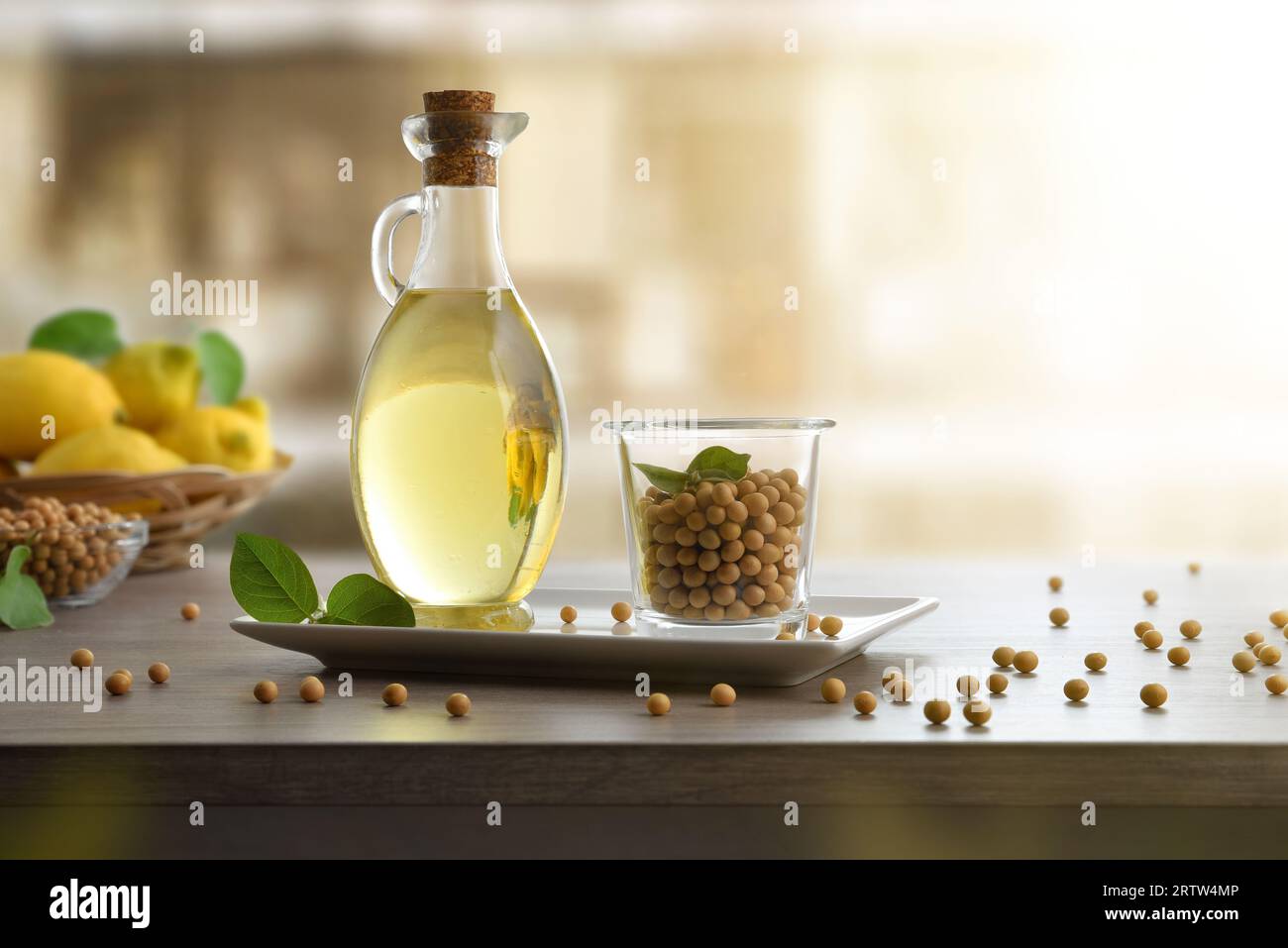 Sojaöl in Glas mit trockenen Sojabohnen in weißer Platte auf Holztisch und weißem isoliertem Hintergrund. Schriftartansicht. Stockfoto