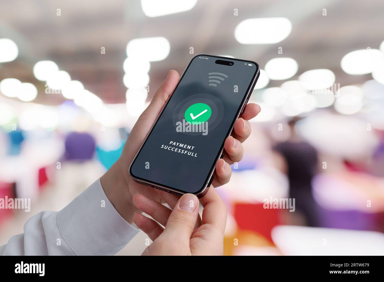 Mobiltelefon in den Händen mit erfolgreicher Zahlungsbenachrichtigung in einem Einkaufsgeschäft, das moderne Transaktionen für einen entzückenden Einkaufswagen zeigt Stockfoto