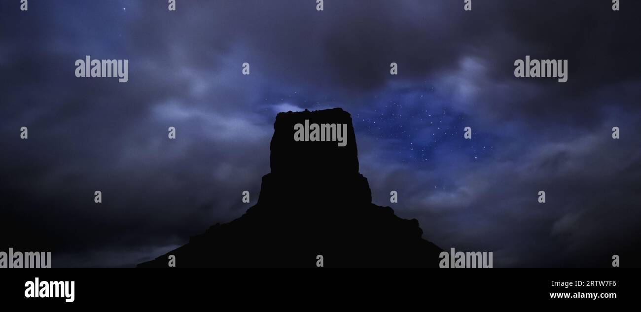 Castle Butte, im Tal der Götter, steht in Silhouette vor einem Wüstenhimmel, der von Sternen gesättigt ist. Stockfoto