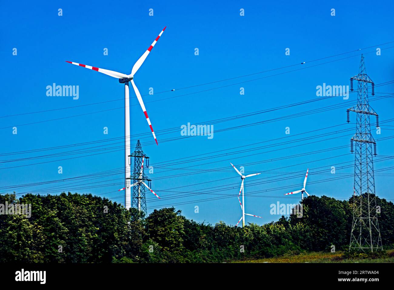 Windmühlen mit Kraftwerken und Drähten. Globale Wirtschaftskrise Stockfoto