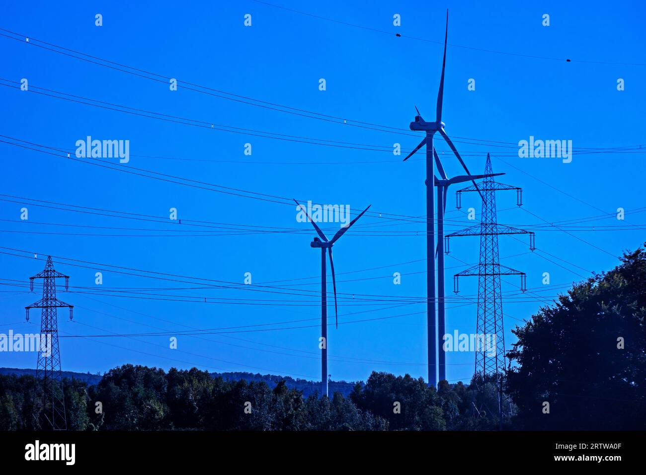 Windmühlen mit Kraftwerken und Drähten. Globale Wirtschaftskrise Stockfoto
