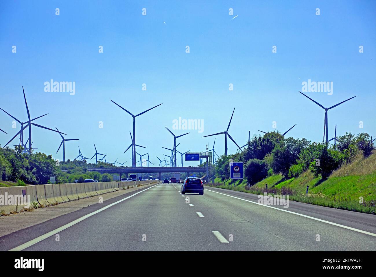 Windmühlen mit Kraftwerken und Drähten entlang der Autobahn um 12:00 Uhr. Wirtschaftskrise in der Welt Stockfoto
