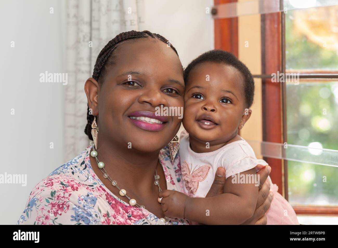 Nahaufnahme einer jungen schwarzen Frau und ihrer kleinen Tochter, die vor der Kamera lächeln Stockfoto