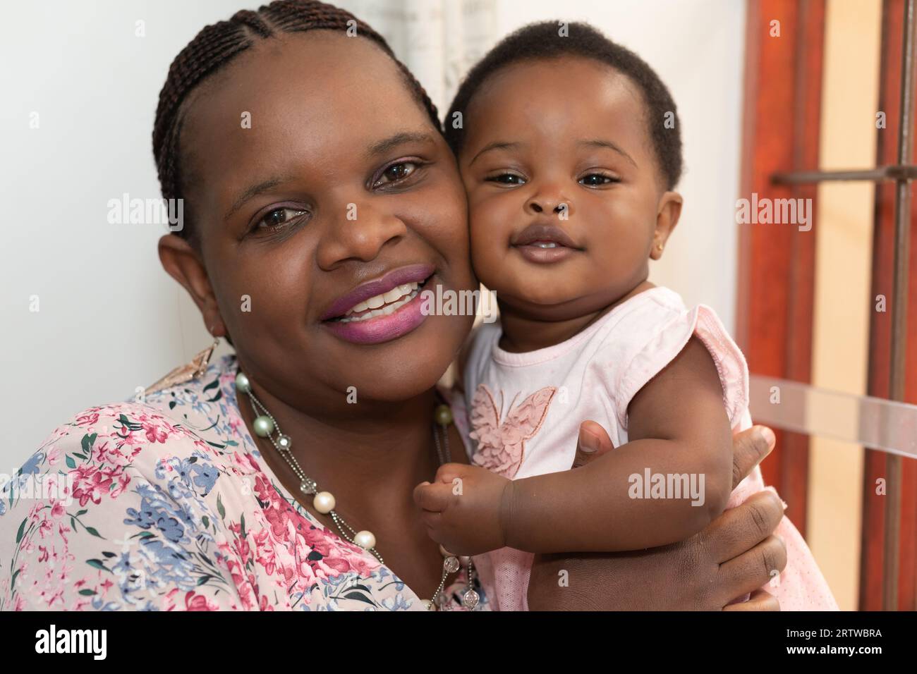 Nahaufnahme einer jungen schwarzen Frau und ihrer kleinen Tochter, die vor der Kamera lächeln Stockfoto