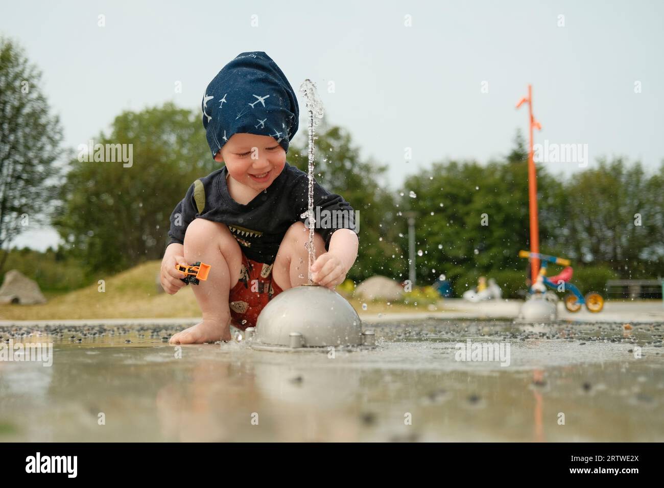 Junge spielt mit Springbrunnen auf dem Spielplatz Stockfoto