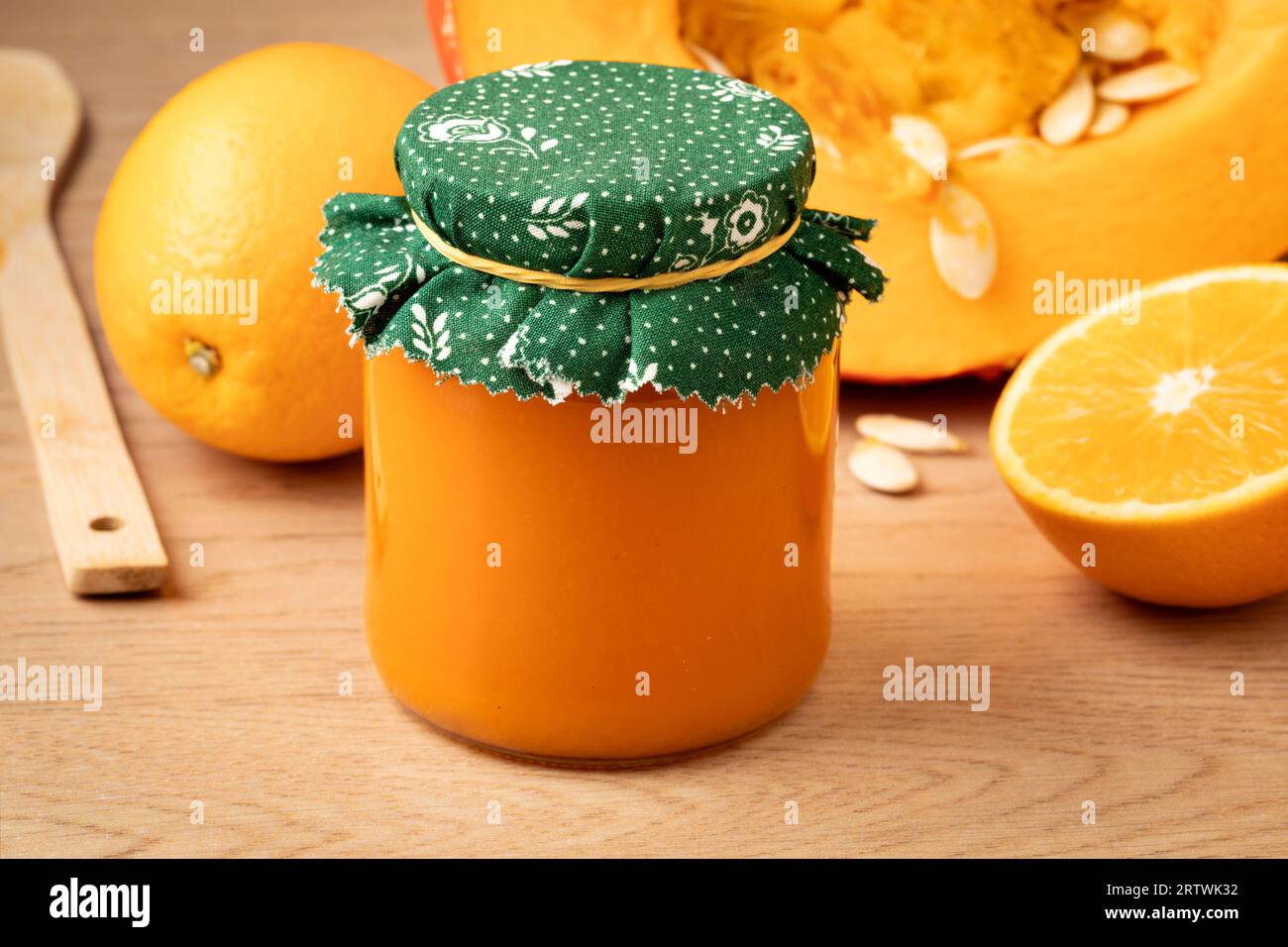 Glas mit hausgemachtem orangen Kürbis und Orangenmarmelade aus nächster Nähe vor einem frischen Kürbis Stockfoto
