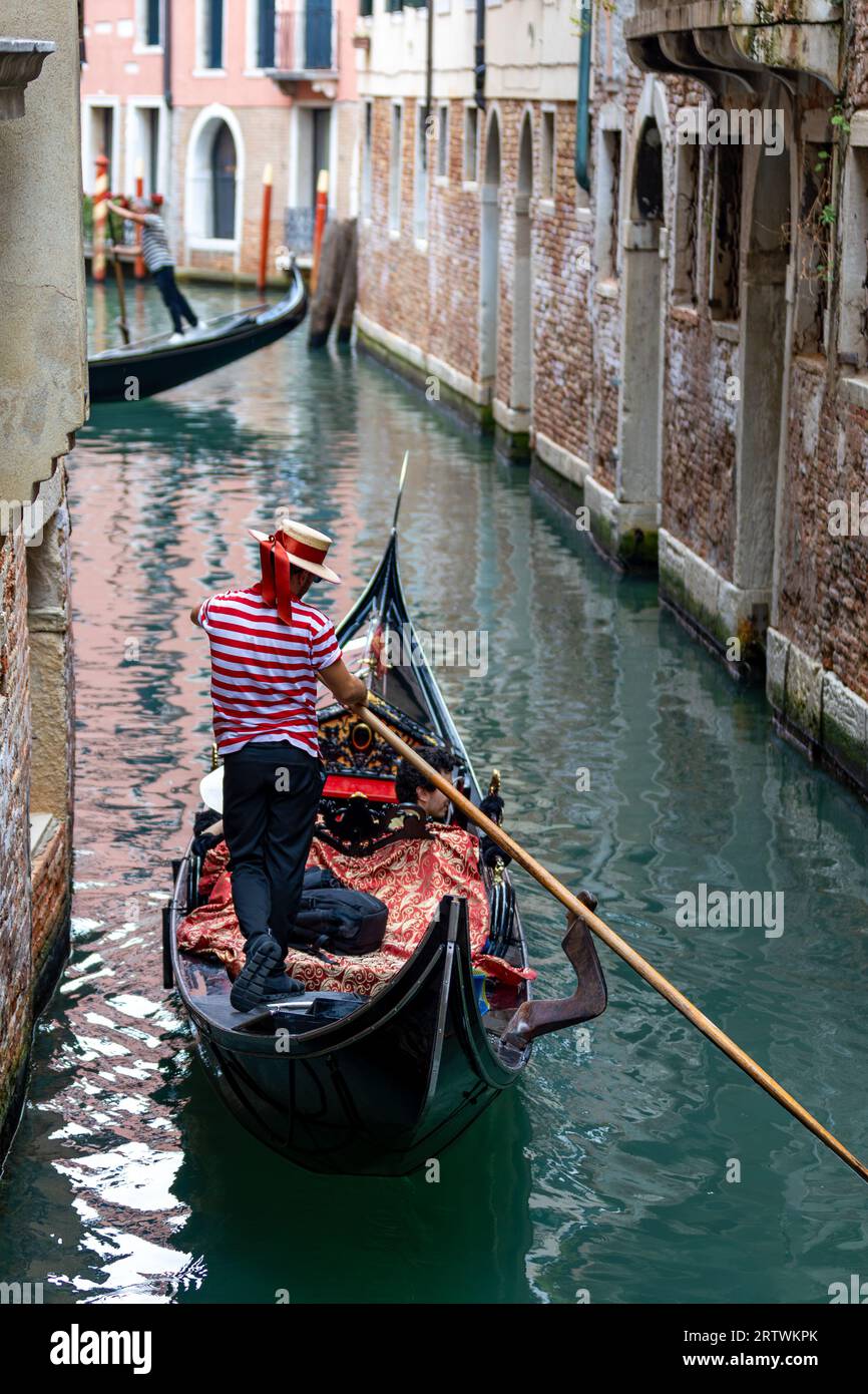 Malerischer Blick auf einen Kanal in Venedig, Italien, mit Gondel und dem berühmten roten gestreiften Hemdgondolier Stockfoto