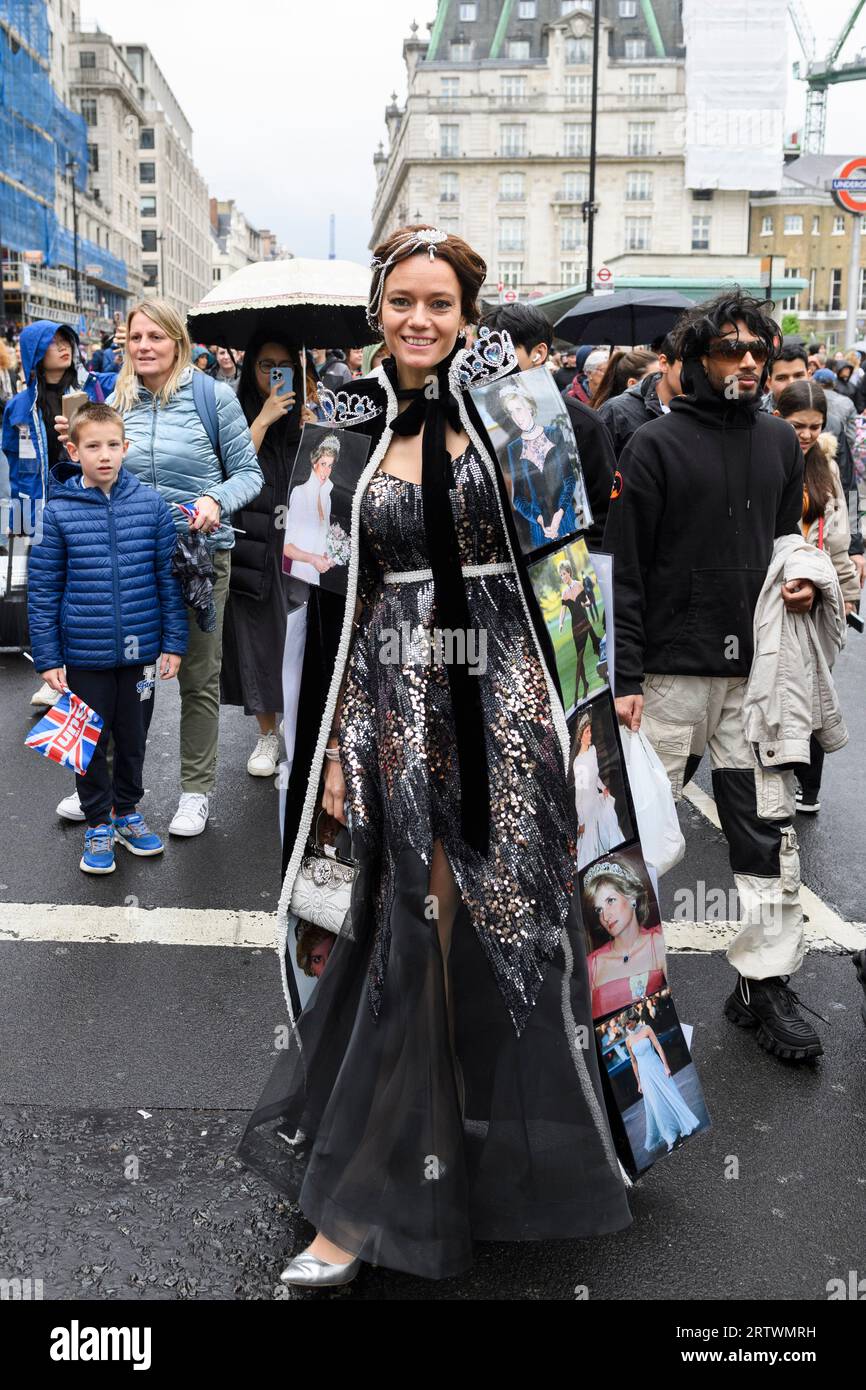 Eine Frau, die ein Abendkleid mit Fotos der verstorbenen Prinzessin Diana trägt, geht Piccadilly im Regen hinunter, ein Teil der großen Menschenmenge steuert Stockfoto