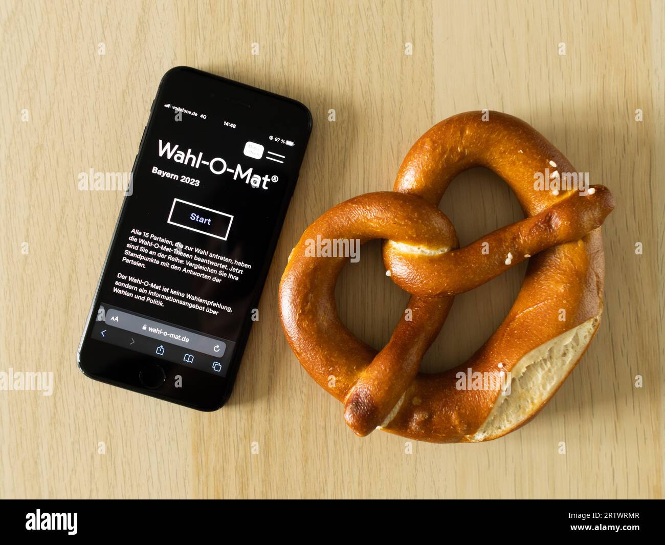 Wahl-O-Mat-Homepage zur Wahl in Bayern 2023 auf dem Handy neben einer Brezel. Demokratie in Süddeutschland. Hilfe bei der Auswahl einer Party. Stockfoto