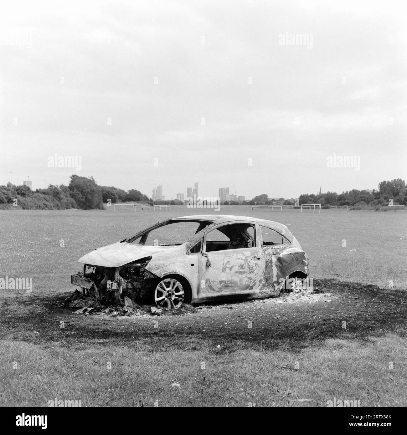 Burn Out Car, Kersal Playing Fields, Salford, UK. Skyline von Manchester City im Hintergrund. Autokriminalität, Diebstahl, antisoziales Verhalten. Juli 2023 Stockfoto