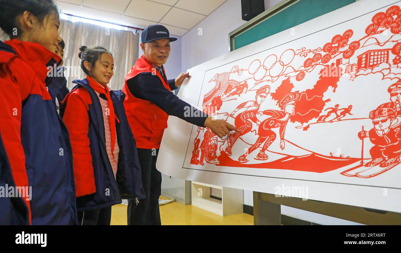 LUANNAN COUNTY, China - 10. Dezember 2021: Grundschüler lernen traditionelle chinesische Papierschneidekunst unter der Leitung von Lehrern, Nord-C Stockfoto