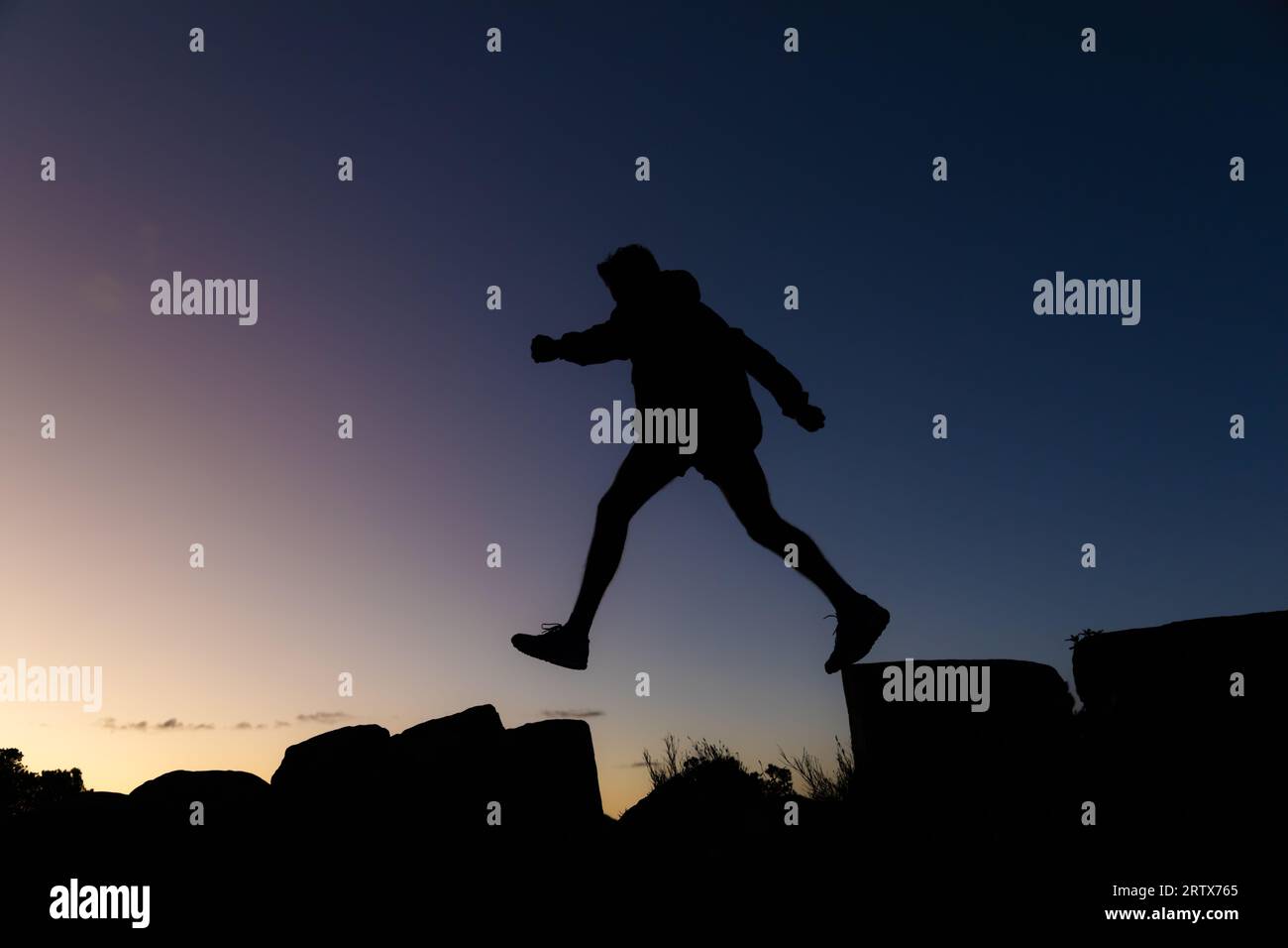 Junger Mann auf einer Wanderung bei Sonnenaufgang in Silhouette Stockfoto