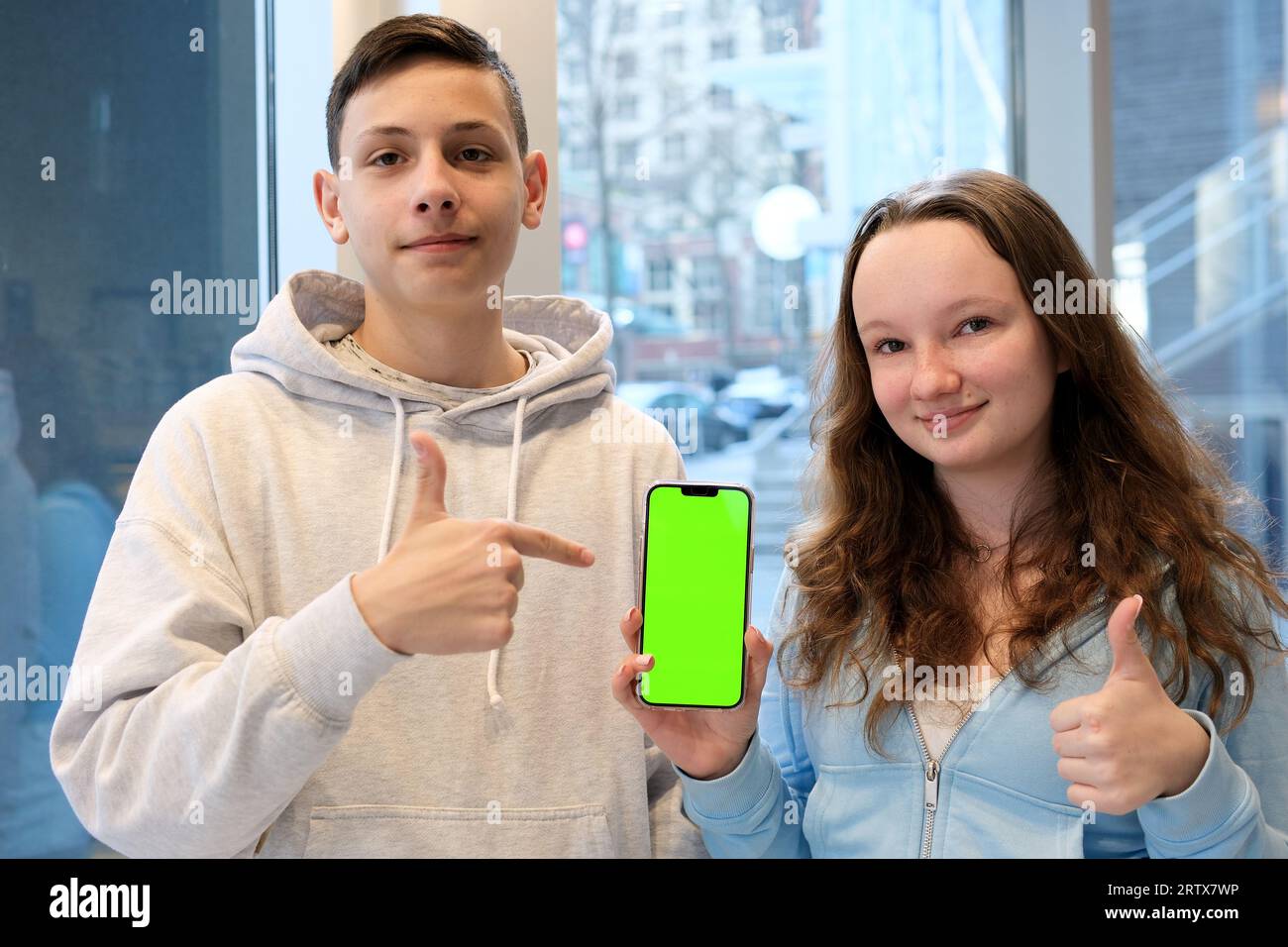 Lächelnder Ginger langhaariger Teen Boy, der ein horizontales Telefon mit Green Screen Chroma Key und sprechenden Wörtern zu Hause zeigt, Produktpräsentation, Teens App, Spiel- und Online-Shop-Werbung. Hochwertige 4K-Qualität Stockfoto
