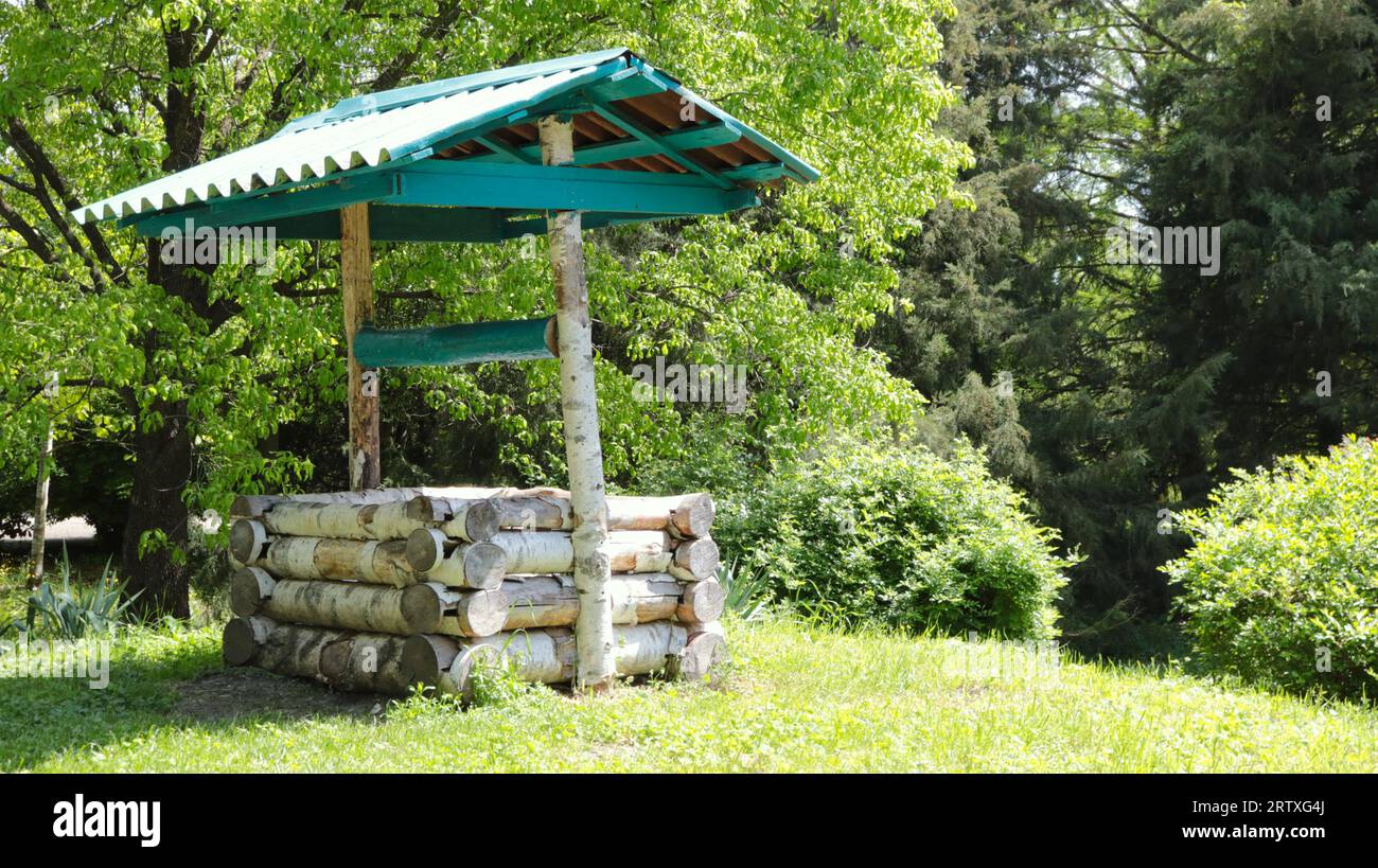 Ein hölzerner Baumstamm unter einem grünen Dach in einem Sommergarten oder Park als authentische Dekoration im slawischen Nationalstil Stockfoto