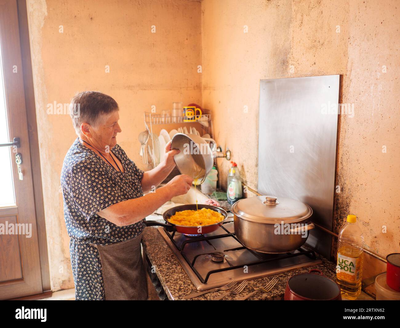 Die alte Frau kocht eine traditionelle spanische Tortilla zu Hause in ihrer Küche, Galicien, Spanien Stockfoto