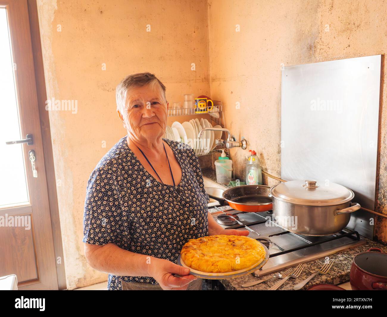 Porträt einer älteren Frau, die eine traditionelle spanische Tortilla zu Hause in ihrer Küche, Galicien, Spanien kocht Stockfoto