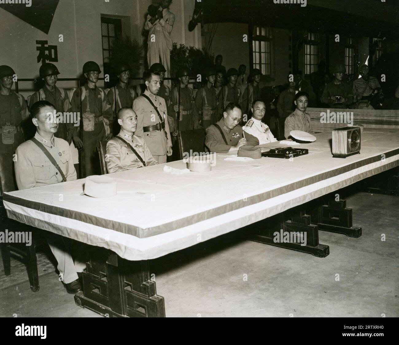 Das Foto zeigt, wie General Ho Ying Chin die Kapitulationsbedingungen unterzeichnete, die die Chinesen den japanischen Beamten bei ihrem Treffen in Nanking (China) zur Unterzeichnung der Friedensbedingungen und Kapitulation an der Zentralen Militärakademie in Nanking am 9. September 1945 übersandten Stockfoto