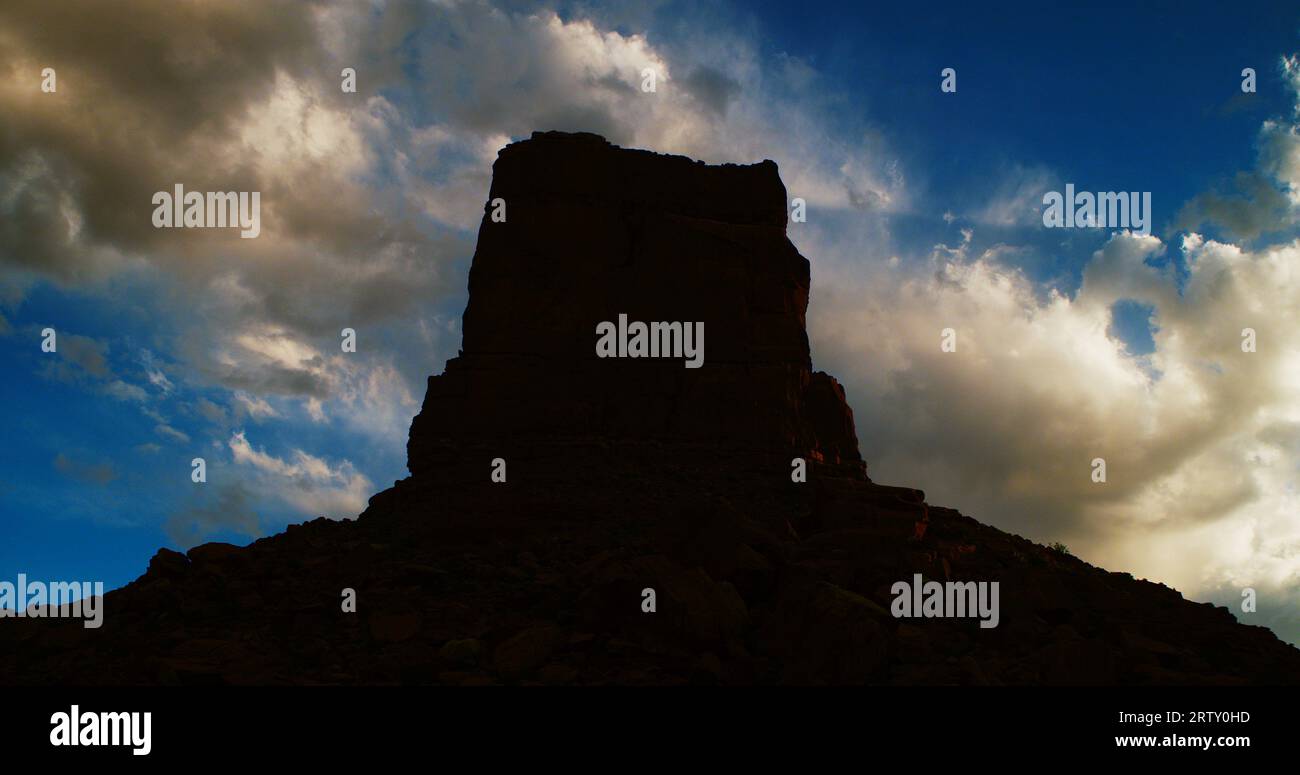 Castle Butte unter einem markanten blauen Abendhimmel und klaren Sturmwolken im Valley of the Gods, Utah. Kühle Töne. Stockfoto