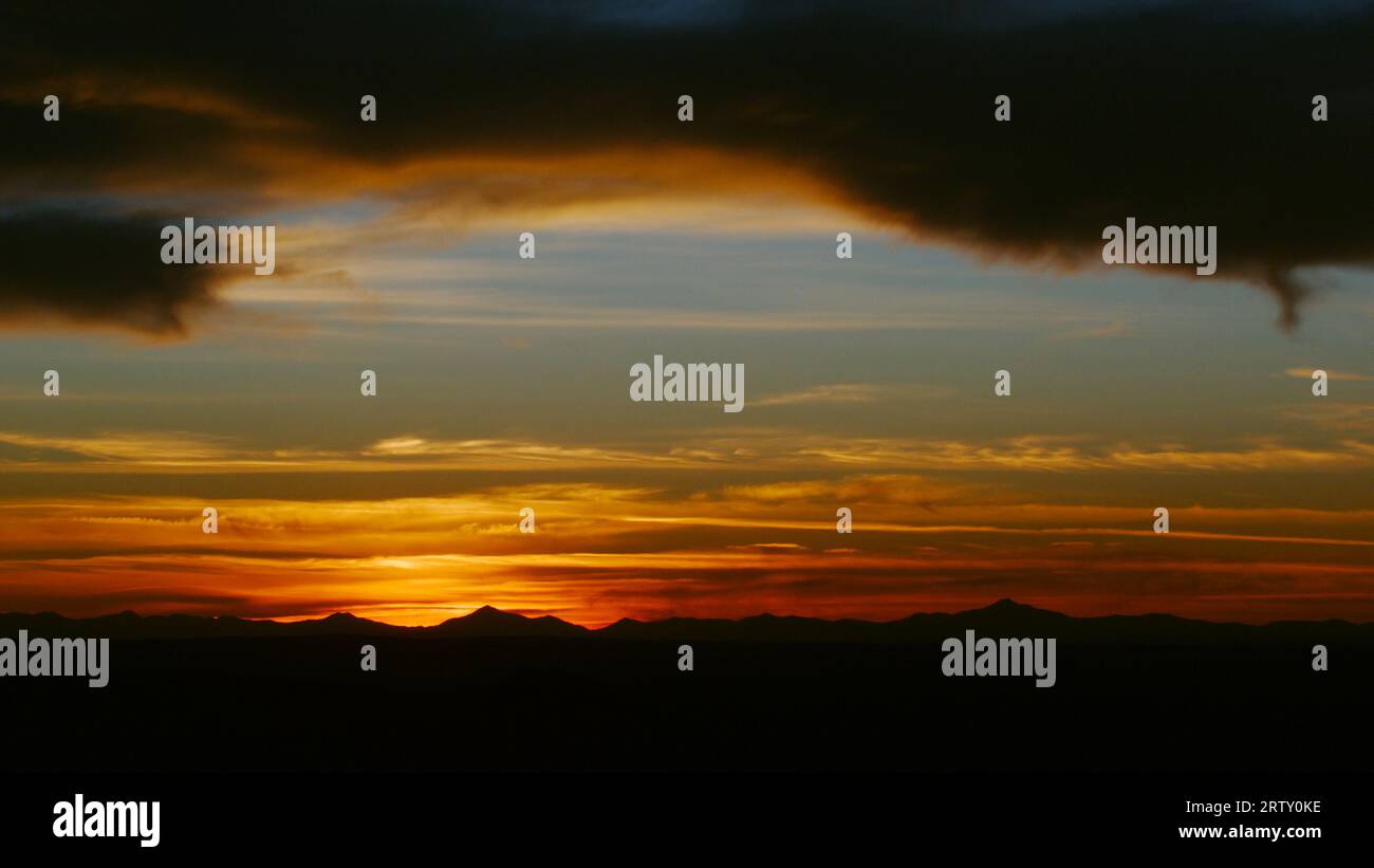 Sonnenuntergang mit schwankender Hitze und ein Wüstenhimmel, der über ferne Berge in brillanten Farben thront. Stockfoto