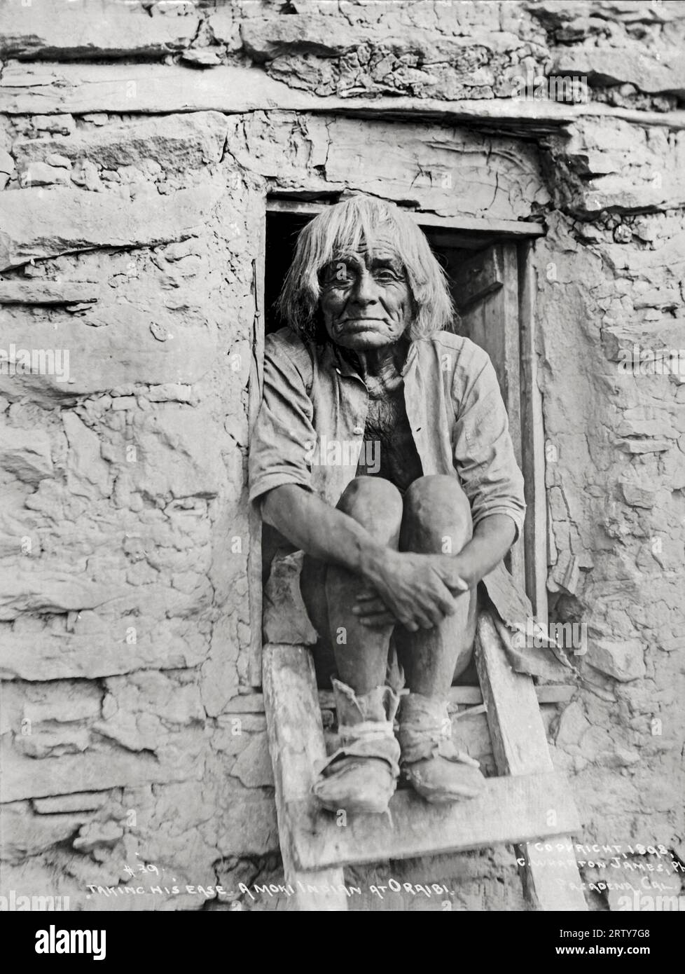 Oraibi, Arizona: 1898 Ein Moki-Mann entspannt sich in seiner Tür. Der Fotograf C. Wharton James wurde später in Phoenix von einer Klapperschlange getötet. Stockfoto
