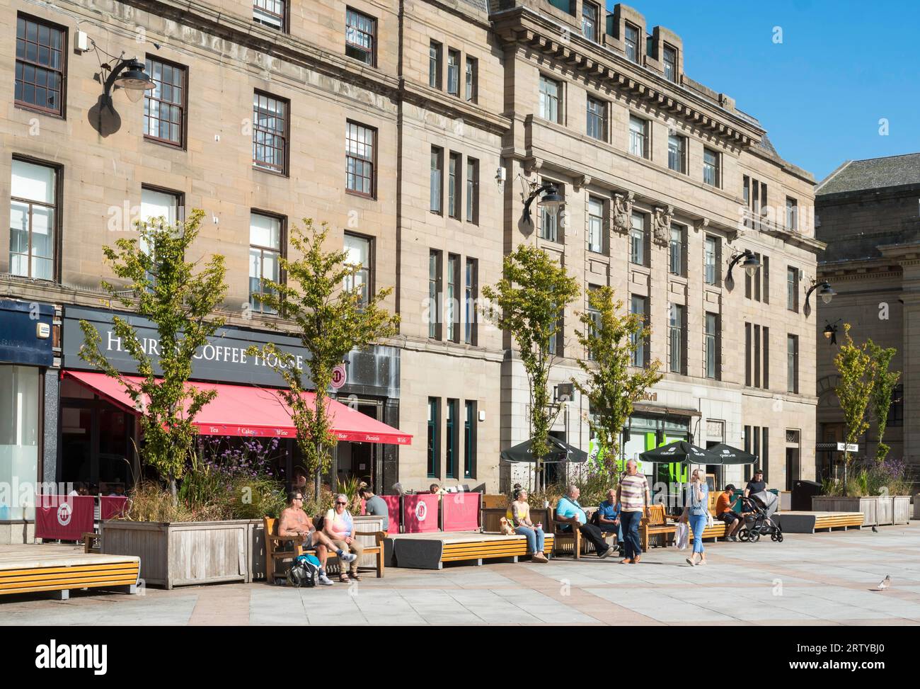 Menschen, die in der Sonne sitzen. City Square, Dundee, Schottland, Großbritannien Stockfoto